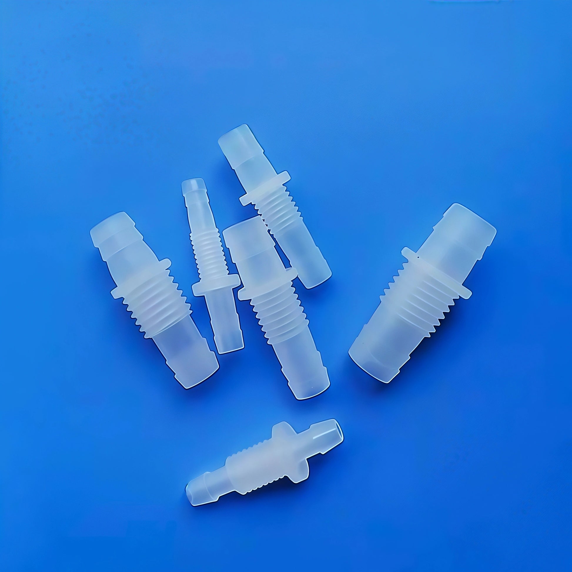 Close-up of plastic bulkhead barb fitting with threaded body and barbed ends, suitable for 5.6mm to 12mm tubing
